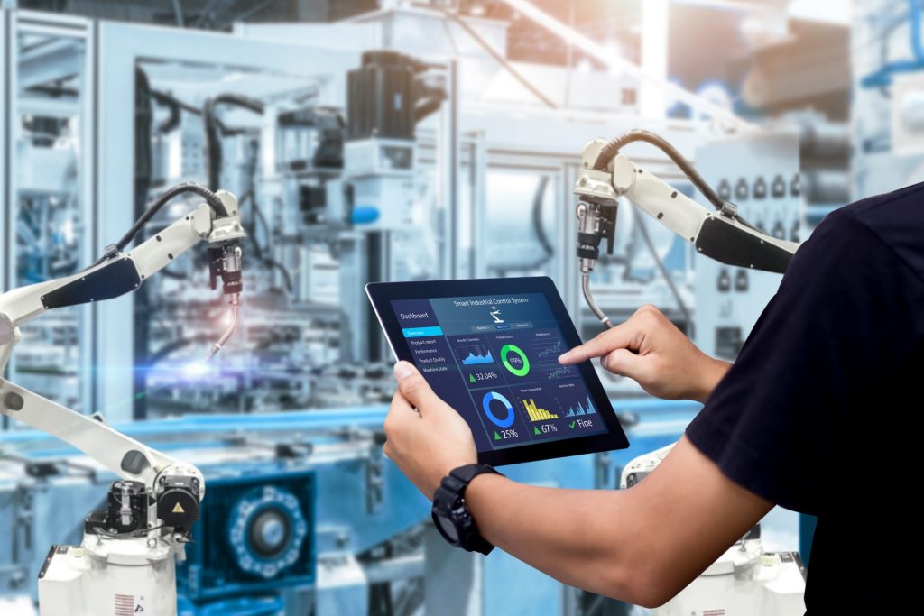 Man using a tablet to monitor manufacturing equipment in a plant